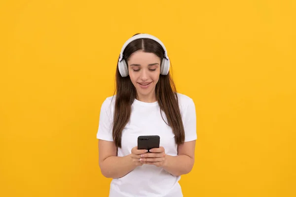 Heureuse dame en chemise blanche écouter de la musique dans les écouteurs et bavarder au téléphone, musique — Photo