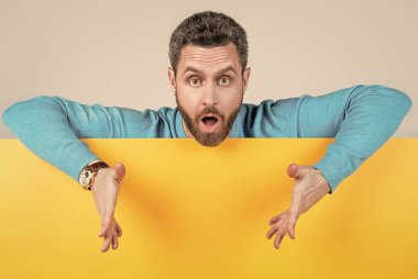 Bilgi için kopyalama alanı olan boş kağıt pankartın arkasındaki şaşırtıcı adam, ürünü sunar.