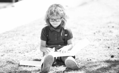 Gözlüklü zeki, kitap okuyan, açık havada kitap okuyan, okula geri dönen bir inek.