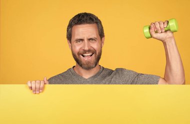 Ağırlık çalışması. Sporcu, halterleri sarı arkaplanda tut.