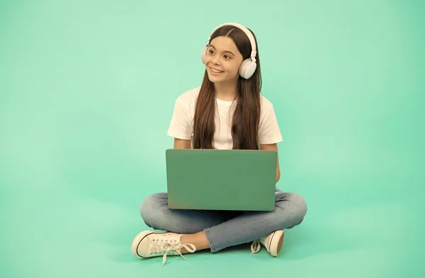 Enfant heureux fille utiliser un ordinateur portable sans fil pour appel vidéo ou écouter webinaire dans les écouteurs, retour à l'école — Photo