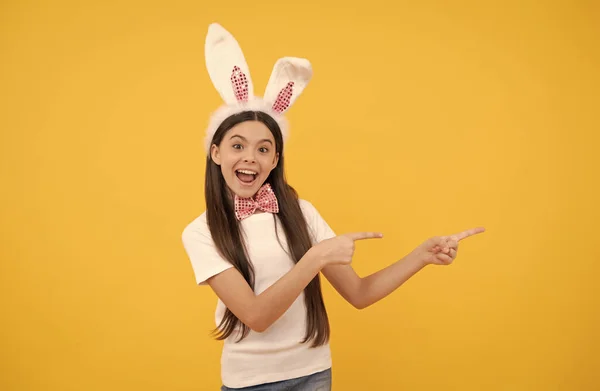 Menina adolescente surpreso em orelhas de coelho apresentando produto ou vendas de compras, espaço de cópia, feriado de Páscoa. — Fotografia de Stock
