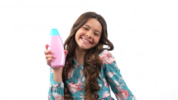 Šťastný dítě dívka s dlouhými kudrnaté vlasy nabídka k použití kůže tělové mléko láhev, péče o pleť — Stock video