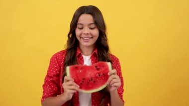 Şaşırmış çocuk sarı arka planda bir dilim kavun meyvesi gösteriyor, meyve.