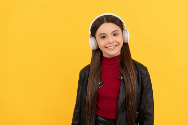 행복 한 십 대 소녀가 헤드폰으로 음악을 듣고 있습니다. 노란색 배경에 복사 공간 과 음악 이 있죠. — 스톡 사진