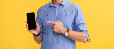 Kırpılmış adam sarı zemin üzerinde akıllı telefonu işaret ediyor, kopyalama alanı, sunum