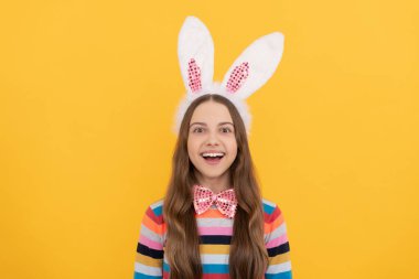 Tavşan kulaklı mutlu Paskalya çocuğu ve sarı arka planda papyon.