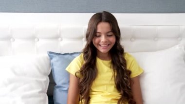 Mutlu çocuk yatakta oturup gülerken bilgisayarda komik film ve komedi izliyor.