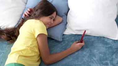 Yatakta telefonla mesajlaşan neşeli çocuk, e-posta
