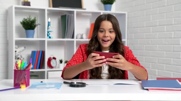 Happy school child jouer à des jeux de téléphone mobile au lieu d'apprendre, jouer à distance — Video