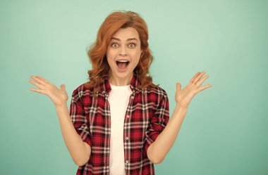 Kıvırcık saçlı, kareli tişörtlü, şaşkın kızıl saçlı kadın.