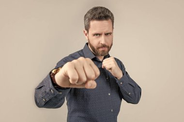 Olgun adam yumruklarını sıkıca kavrayarak dövüş pozisyonunda duruyor. Günlük iş tarzı, yarışma.