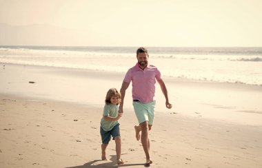 Mutlu baba ve oğul koşuyor ve yaz tatilinde eğleniyor. Aile tatilinde.