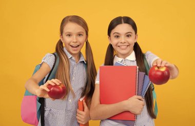 Mutlu ilkokul çocukları lezzetli elmalar, meyve sarısı arka plan, gıda bilgisi sahibi.