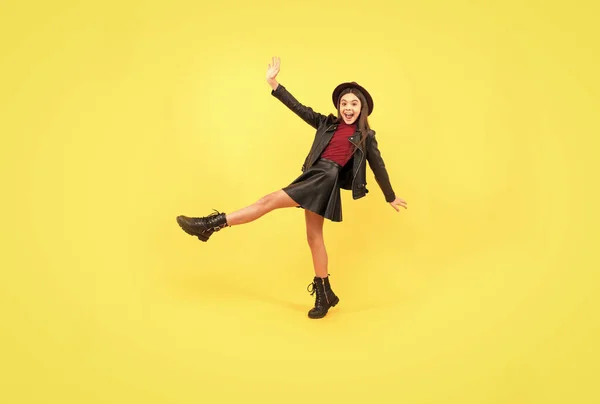 Boldog tini lány kalap és bőr ruhák, hogy széles lépés előre, gondtalan — Stock Fotó