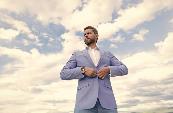 Красивый зрелый мужчина бизнесмен в костюме проверить время на наручные часы на фоне неба, формальная одежда. — стоковое фото