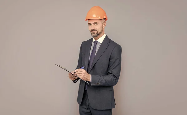 Zelfverzekerde zakenman in helm hold map. deskundigheid op het gebied van veiligheid. man met een hoed die notities maakt. — Stockfoto