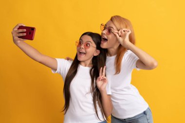 Mutlu anne ve kız çocuğu akıllı telefonda selfie için poz veriyor.