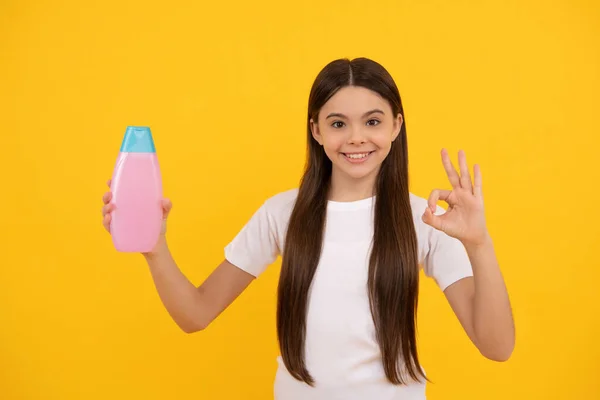 Χαρούμενο παιδί κρατήστε τα μαλλιά conditioner μπουκάλι δείχνουν εντάξει στο κίτρινο φόντο, φροντίδα του δέρματος — Φωτογραφία Αρχείου
