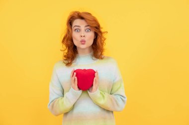 Sarı arka planda kırmızı kalpli kızıl saçlı komik bir kadın. Sevgililer Günü
