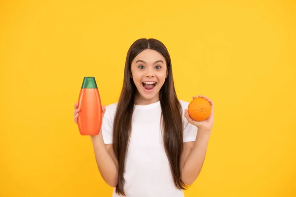 Úžasný dospívající dívka dlouhé vlasy s tělové mléko a grapefruit na žlutém pozadí, kosmetické — Stock fotografie