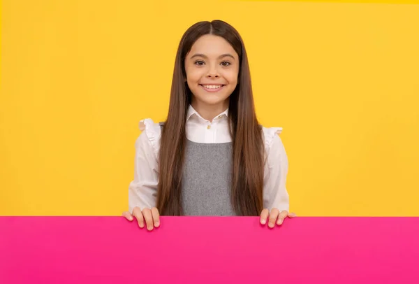 Niño sonriente detrás de la hoja de papel rosa en blanco para el espacio de copia, publicidad — Foto de Stock