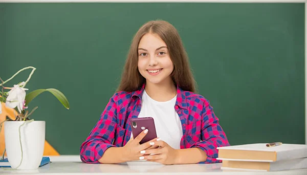 Heureux adolescent fille dactylographier message sur téléphone mobile au lycée au tableau noir, école — Photo