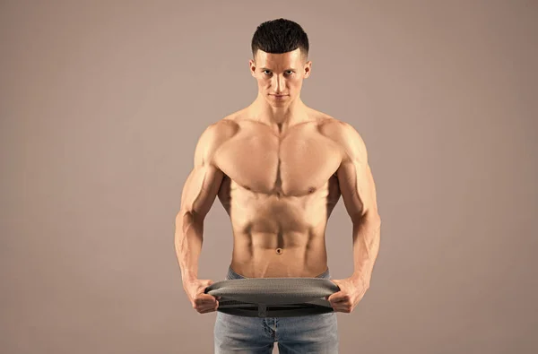 Bodybuilder do muscle building workout with resistance band grey background, training — Stock Photo, Image