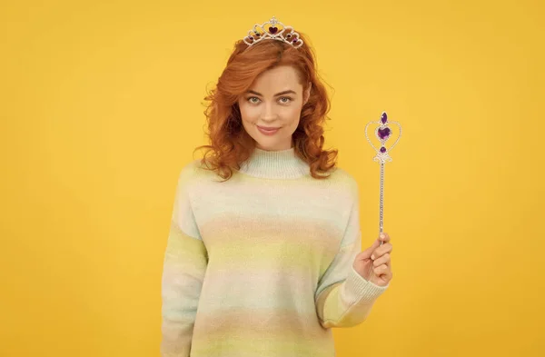 smiling redhead woman in queen crown with magic wand, wish