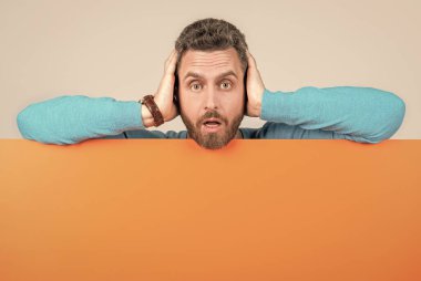 Boş turuncu kağıt pankartın arkasında, duyuru için fotokopi aletiyle şok olmuş olgun bir adam..