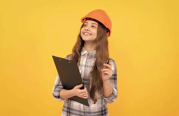 Szczęśliwy nastolatek dziewczyna w kasku i szach koszula robi notatki na schowku, inspektor — Zdjęcie stockowe