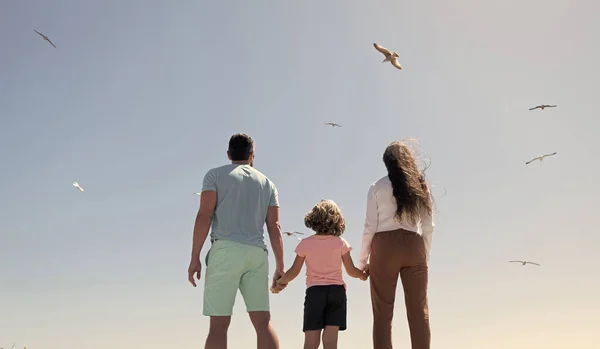 Family of mom father and child looking in future hold hands in summer, back view, summer vacation. — Stock Photo, Image