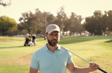 Golf sopası takmış altın şapkalı adam yeşil çimlerde golf oynuyor.