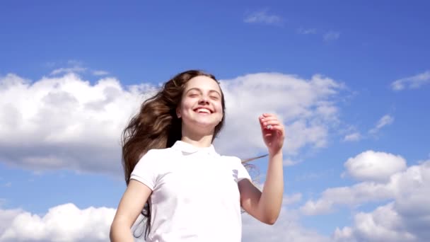 Щаслива дитина насолоджується сонцем і вітром з довгим волоссям на фоні неба, насолода — стокове відео