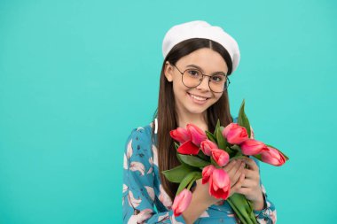 Bere takmış, laleli bir çocuk. Anneler ya da kadınlar günü. Gözlüklü çocuk çiçekleri tutuyor.