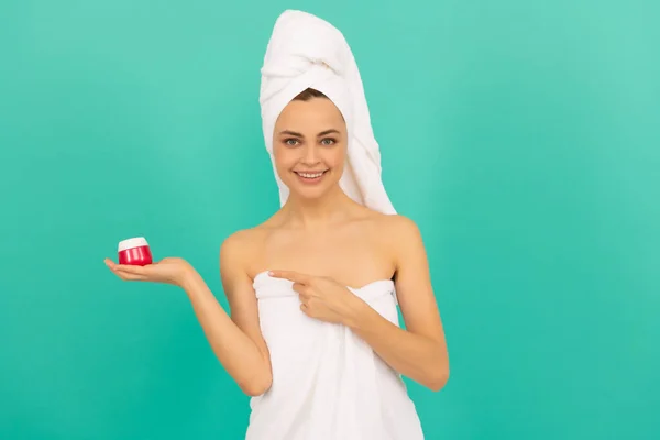 Gelukkig jong vrouw in handdoek punt vinger op huid crème op blauwe achtergrond — Stockfoto