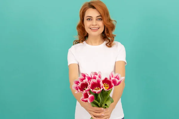 glad woman with tulip flower bouquet on blue background