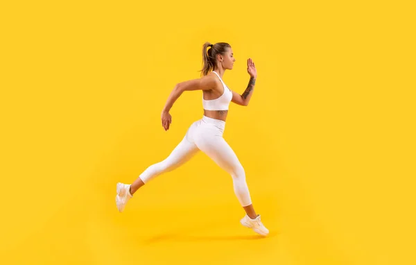 Corridore ragazza sportiva in esecuzione su sfondo giallo — Foto Stock