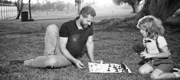 Pai e filho jogar xadrez na grama no parque de verão, xadrez — Fotografia de Stock