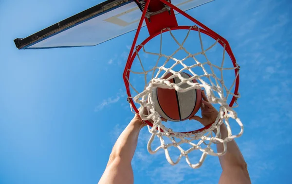 Pelota de baloncesto volando a través de la cesta en las manos de los jugadores en el cielo fondo, baloncesto —  Fotos de Stock
