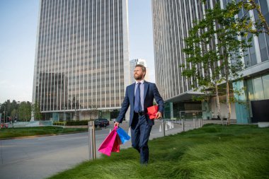 Adam alışveriş torbalarını tutuyor. Erkekler günü. Paketleri olan mutlu bir iş adamı. satış ve indirim.
