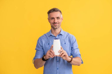 Sarı arka planda saç şampuanı gösteren adam, kozmetik.