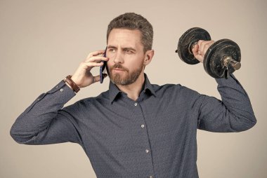 Güçlü sakallı iş adamı halterle eğitilmiş ve akıllı telefondan konuşan, merhaba.