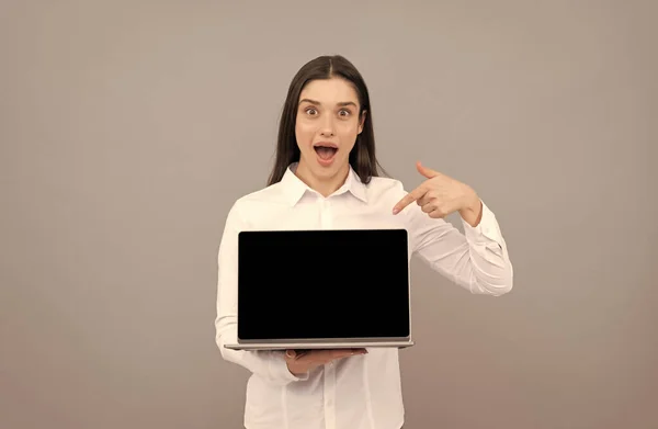 Překvapená podnikatelka prezentující obrazovku notebooku pro online prezentaci, ukazující prst. — Stock fotografie