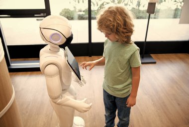 Robot çocuğa yardım sağlıyor. Otomasyon. Yapay zeka oğlanla etkileşim halinde