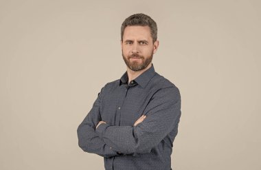 Her zaman kendinden emin olabilirsin. Kendine güvenen bir adam kollarını çapraz gri arka planda tutar. Sıradan stil