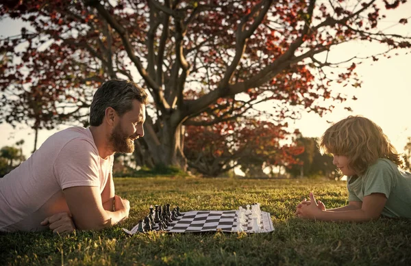 Père et fils jouant aux échecs sur l'herbe dans le parc. la fête des pères. famille heureuse. parentalité et enfance. — Photo