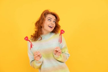 Kırmızı kalpli mutlu kızıl kız sarı arka plana yapışıyor. Aşk