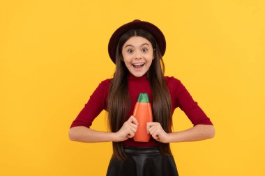 Şapkalı şaşkın kız şampuanı tutuyor. Gençler için kozmetik ürün sunumu.