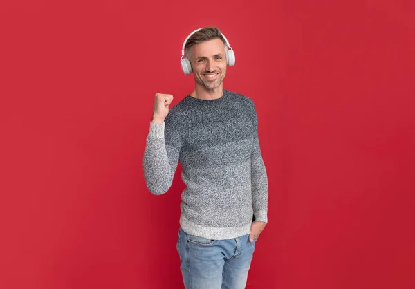 Hombre feliz escuchar música en los auriculares haciendo el gesto ganador fondo rojo, escuchando —  Fotos de Stock